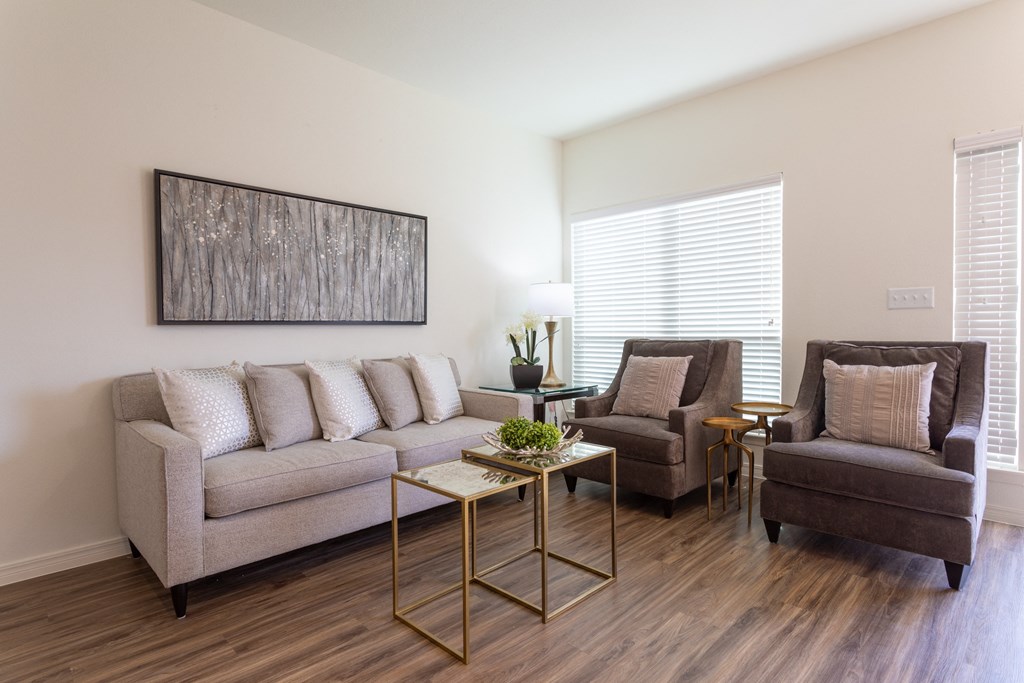 A living room with a grey couch, two chairs and a coffee table.