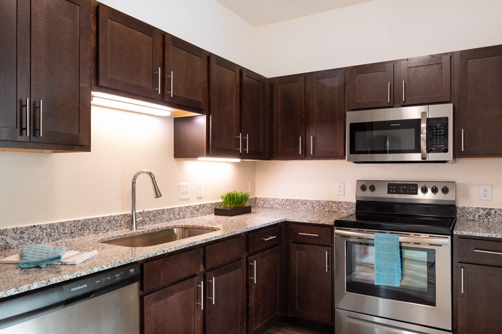 A kitchen with brown cabinets and a stainless steel oven.