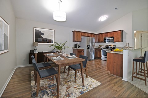 A kitchen and dining room with wooden floors and furniture.