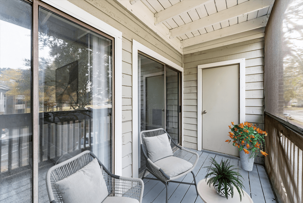 A balcony with two chairs and a table with a plant on it.