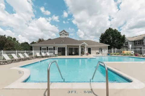 A large swimming pool with a diving board and a building in the background.