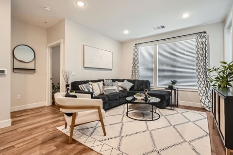 A living room with a black couch and a wooden chair.