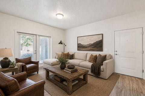 A living room with a brown leather couch, a wooden coffee table, and a painting on the wall.
