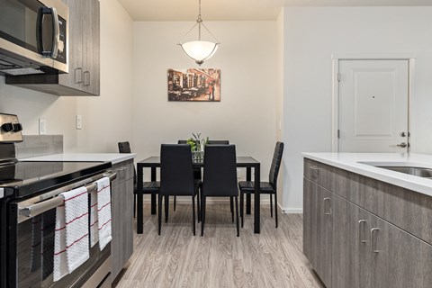 an open kitchen and dining room with a black table and chairs and a kitchen counter