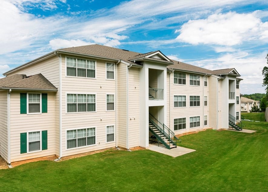 a large apartment building with a green lawn and a blue sky