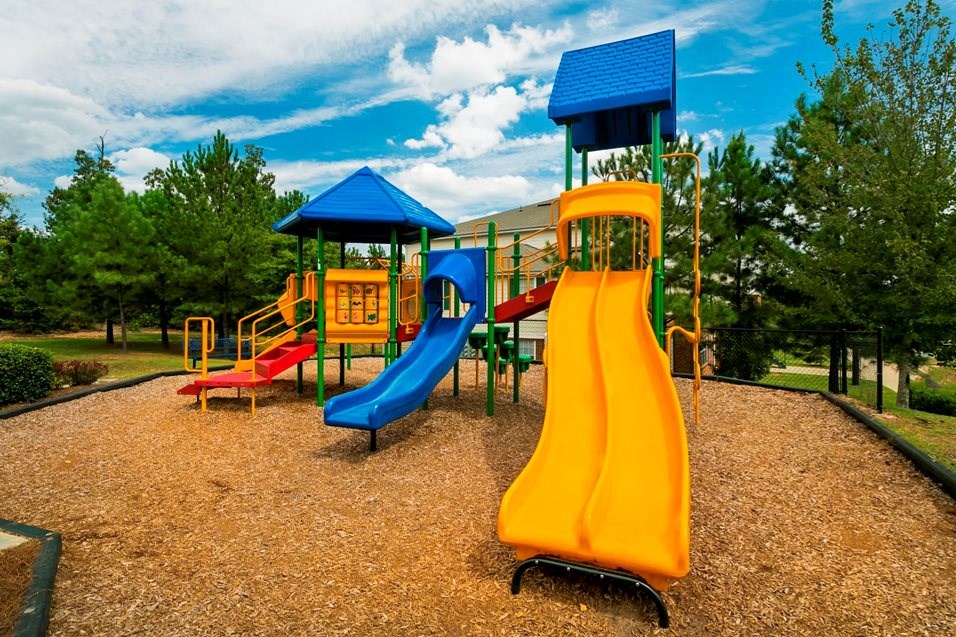 a playground with a yellow slide and a blue pavilion