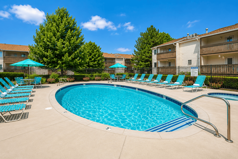 A swimming pool surrounded by chairs and trees.