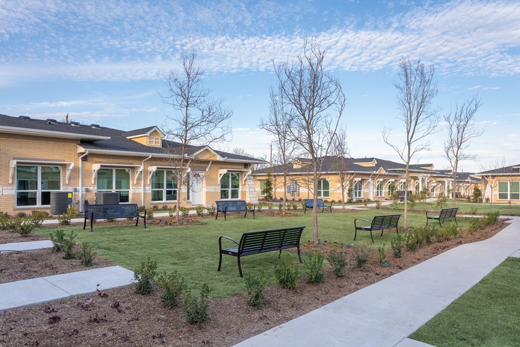 a park with benches and houses in the background