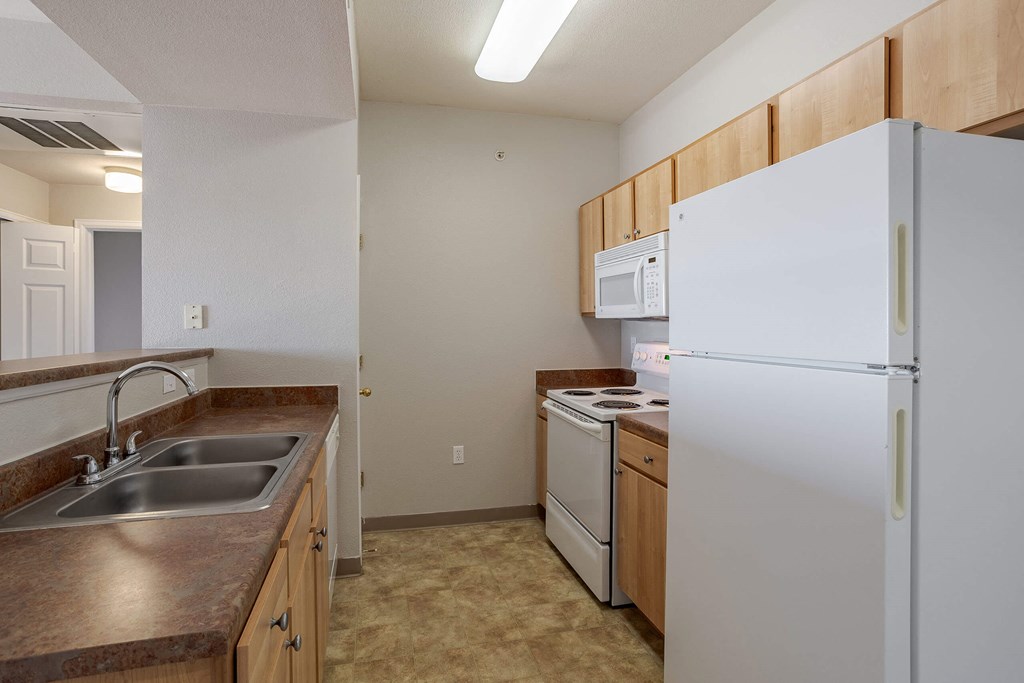 a kitchen with a sink and a refrigerator a kitchen with a sink and a refrigerator at Stetson Meadows Apartments, Colorado Springs