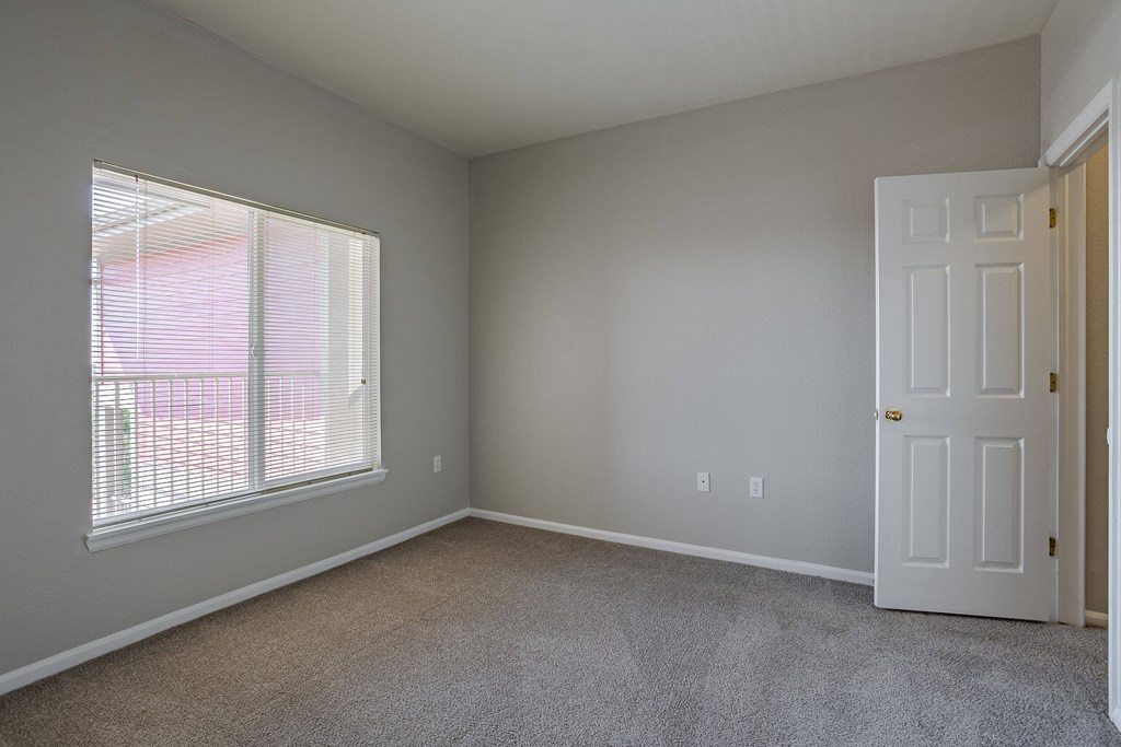 an empty bedroom with a large window and a white door an empty bedroom with a large window and a white door at Stetson Meadows Apartments, Colorado