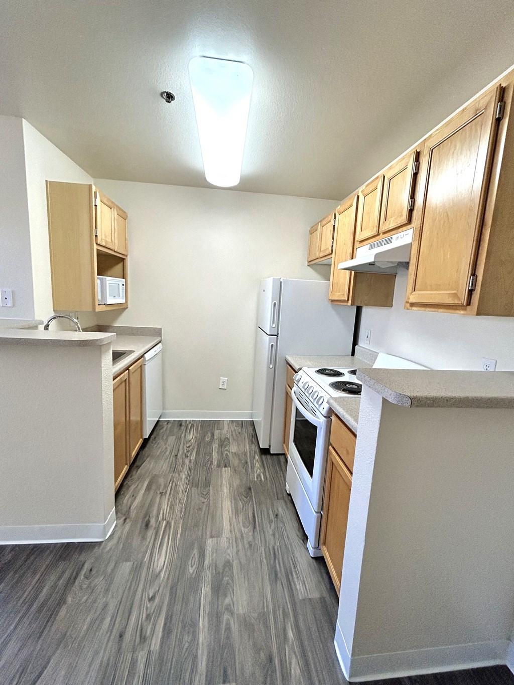 an empty kitchen with wood floors and white appliances