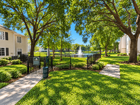 A green lawn with a fence and a sign in front of a building.