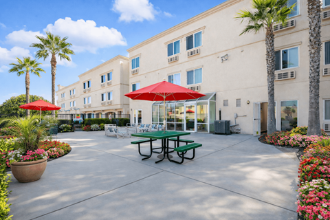 A sunny day at the outdoor seating area of a building with tables and chairs.