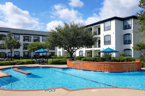 A swimming pool in front of a white apartment building.