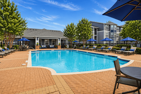 A swimming pool surrounded by a brick patio and lounge chairs.