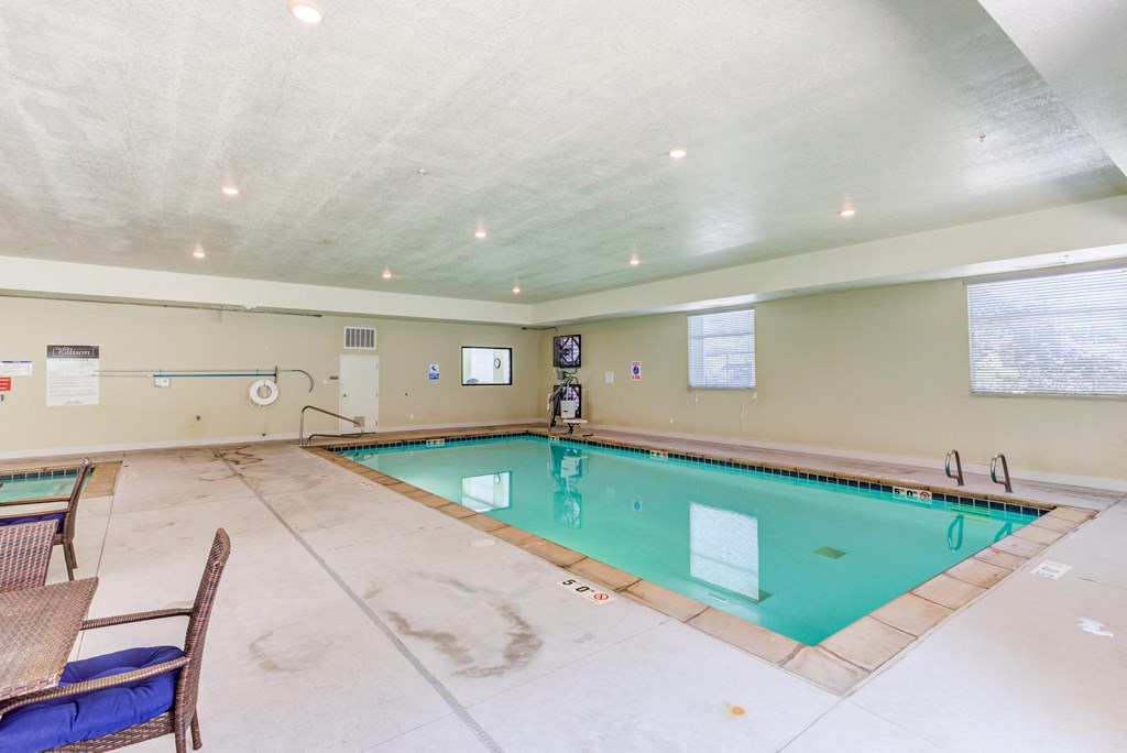 A large indoor swimming pool with a lounge chair and a table.