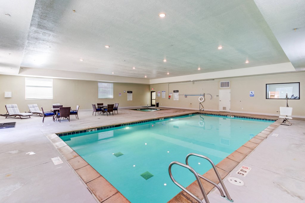 A large indoor swimming pool with a diving board and lounge chairs.