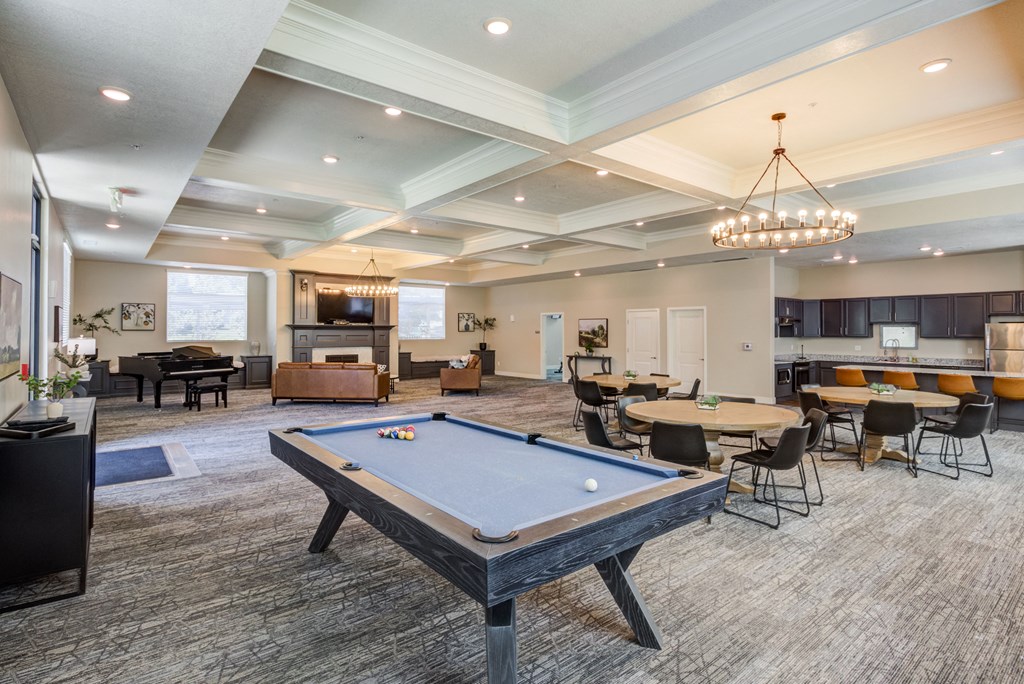 A pool table is in the middle of a room with a bar and a dining table.