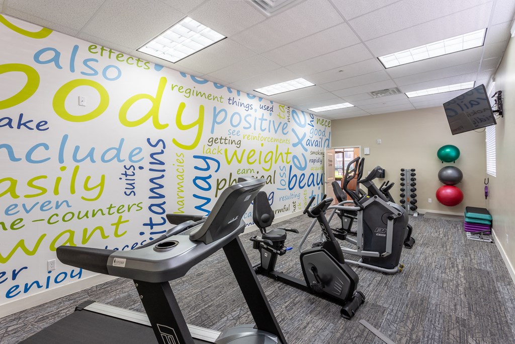 A gym with a wall covered in words related to fitness and exercise.