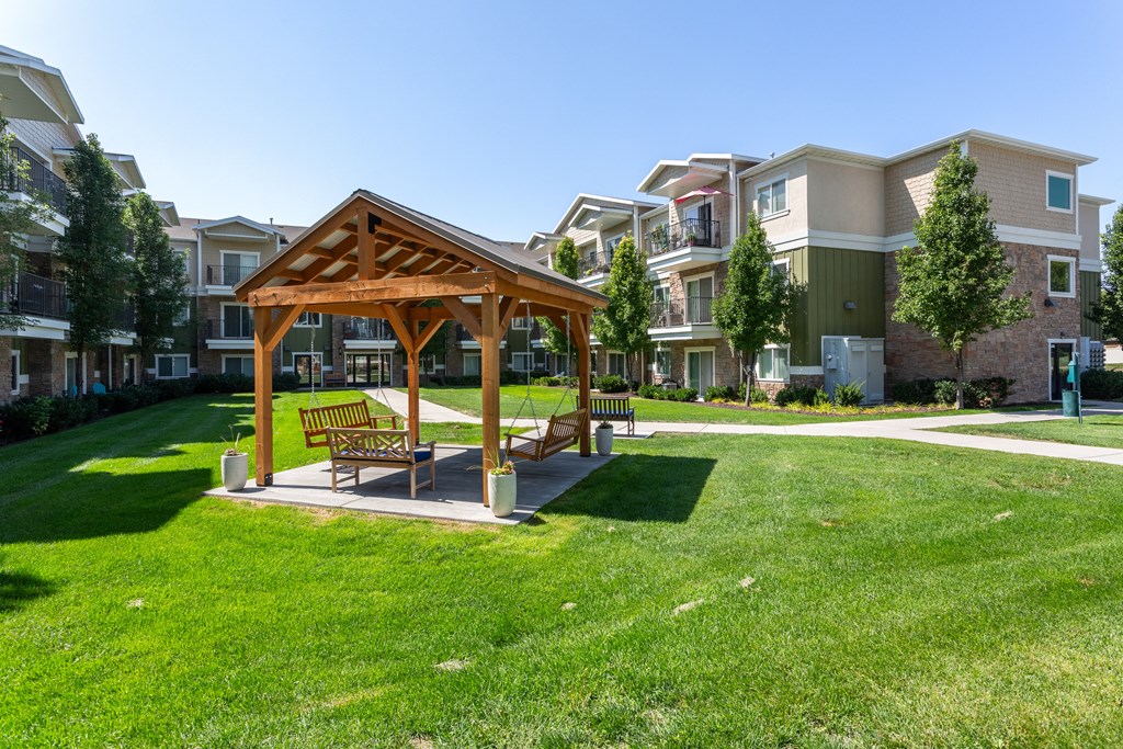 A wooden pavilion with a bench is in the middle of a grassy area.