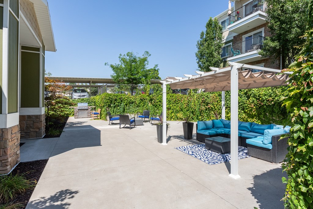 A patio with a white pergola and blue cushions.