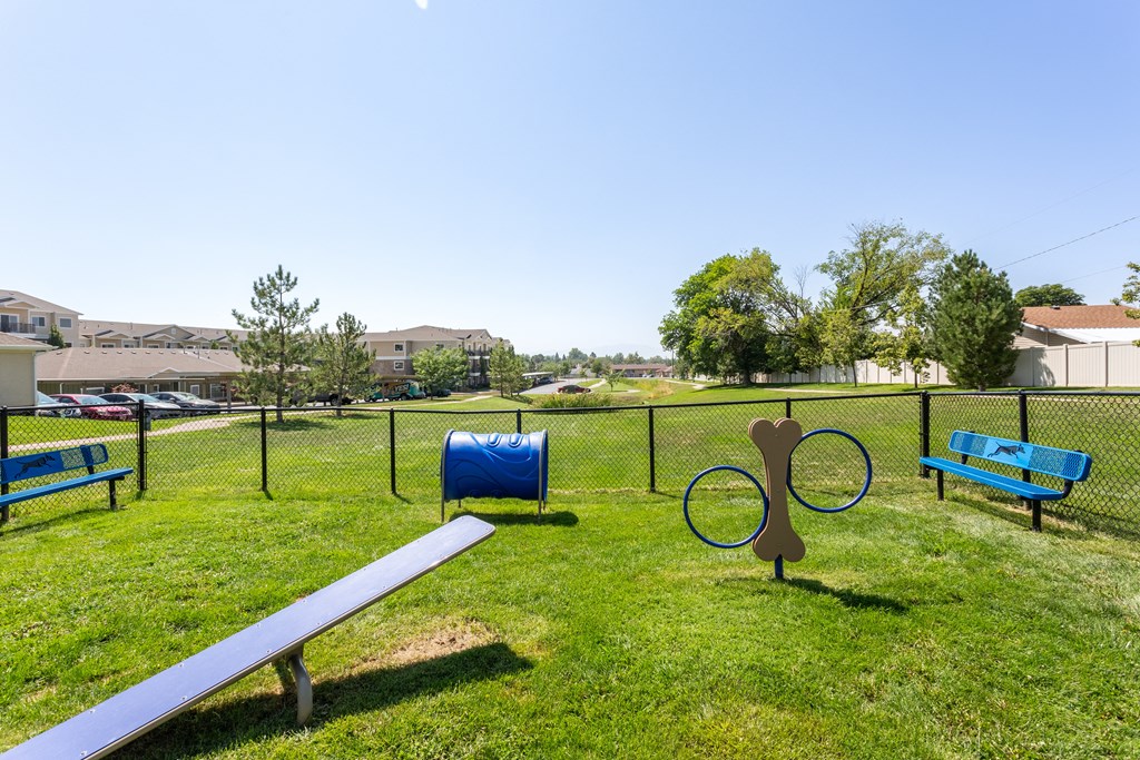 A park with a blue bench and a metal dog sculpture.