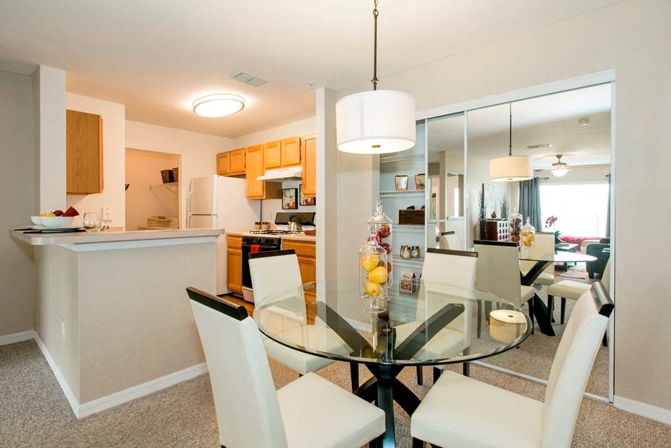 a dining room and kitchen with a glass table and chairs