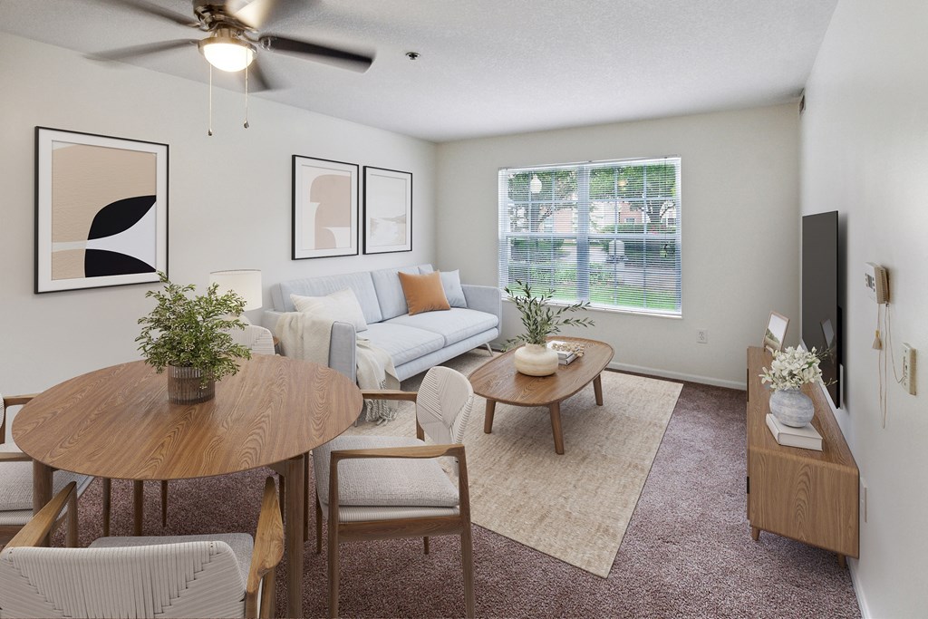 A living room with a couch, chairs, a coffee table, and a ceiling fan.