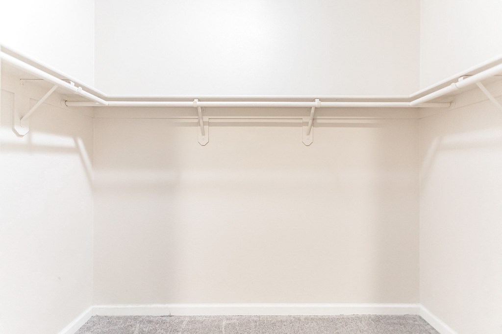 a walk in closet with white walls and white hangers