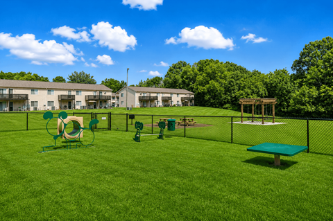 A playground area with a green slide, a green bench, and a green trampoline.