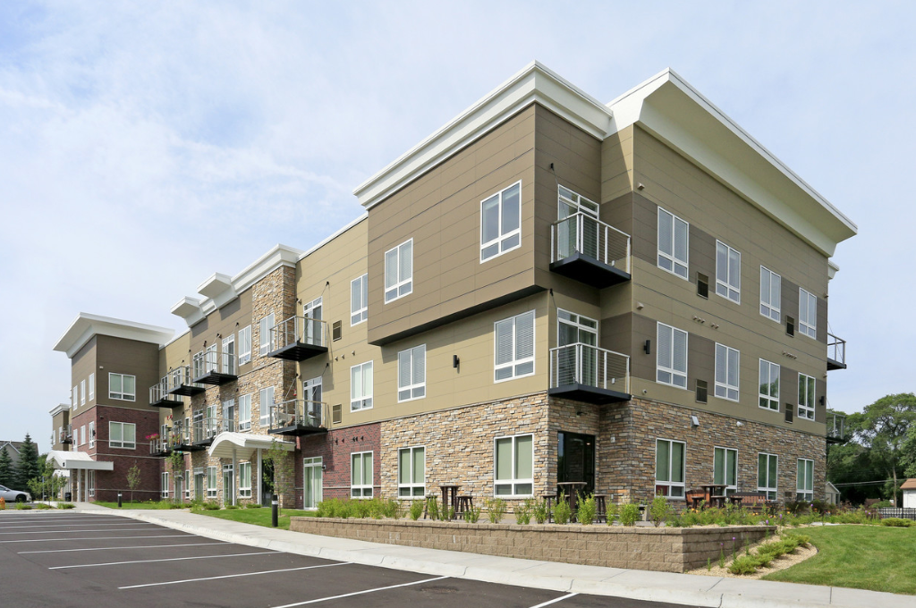 an exterior view of an apartment building with a parking lot