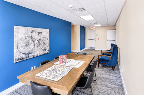 Community meeting room with dining table and artwork at The Ellison Apartments, Layton, Utah