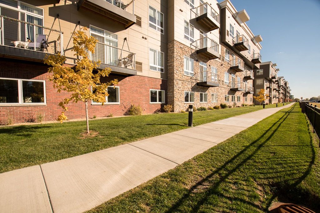 an empty sidewalk in front of an apartment building