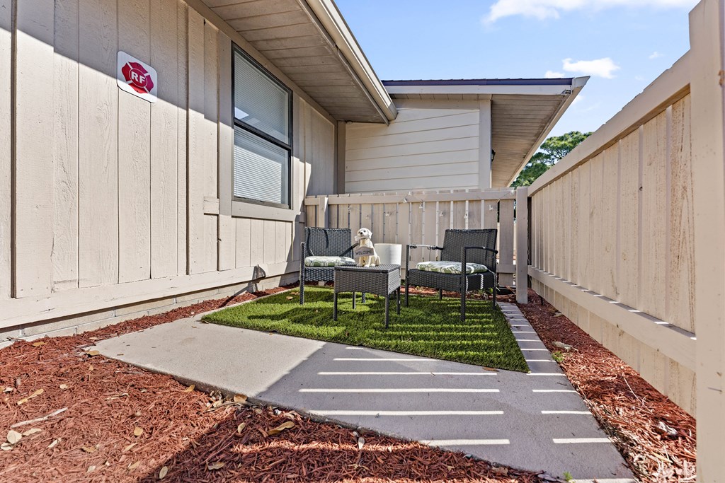 a patio with a table and chairs in front of a house