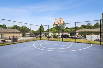 A basketball court with a hoop and a fence surrounding it.