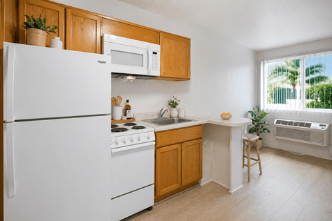 A kitchen with white appliances and wooden cabinets.