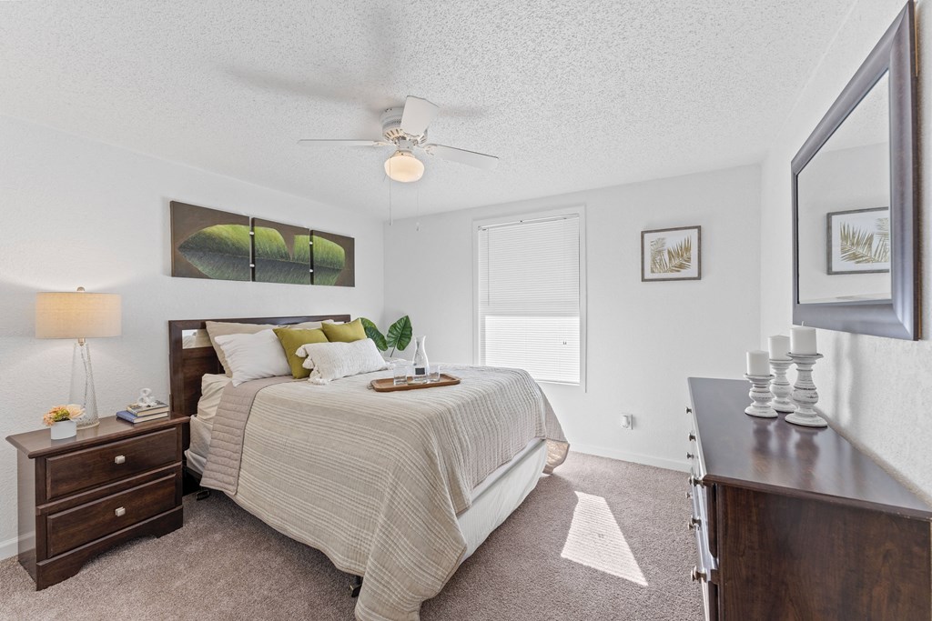 a bedroom with a bed and a dresser and a ceiling fan