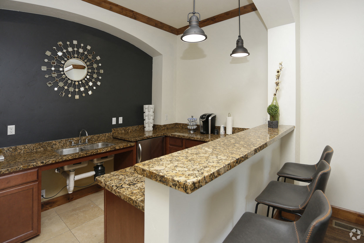 a kitchen with granite counter tops and a bar with two chairs