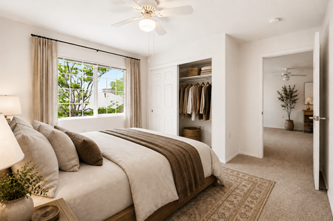 A bedroom with a large bed and a ceiling fan.