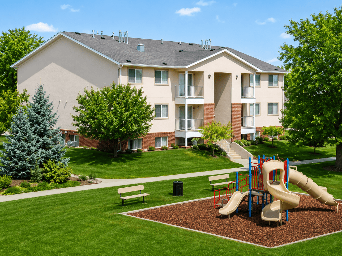 A playground with a slide and a bench in front of a building.
