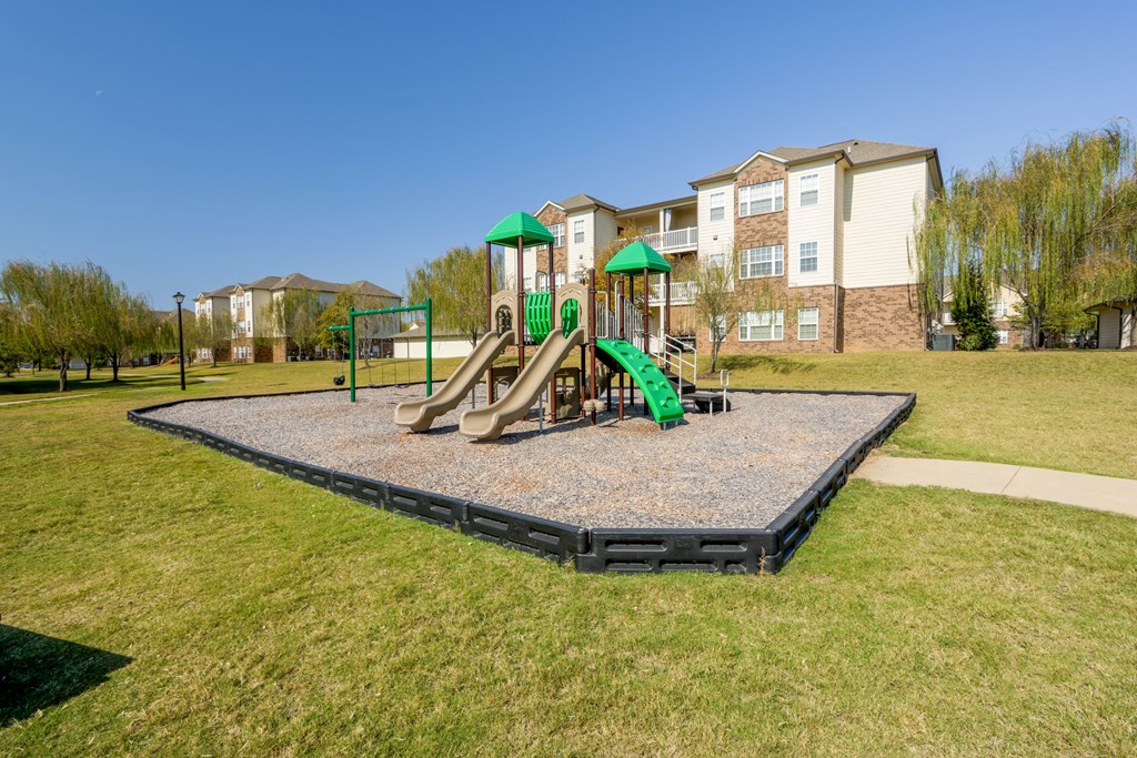 A playground with a green slide and a green canopy.