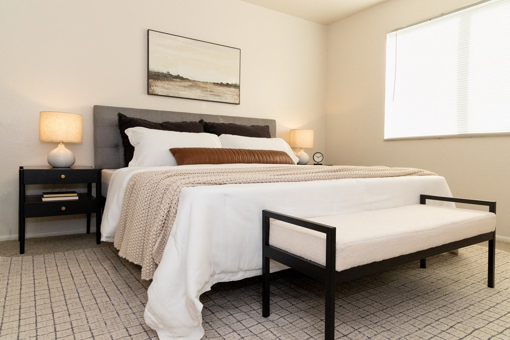 a bedroom with a bed and two nightstands and a window