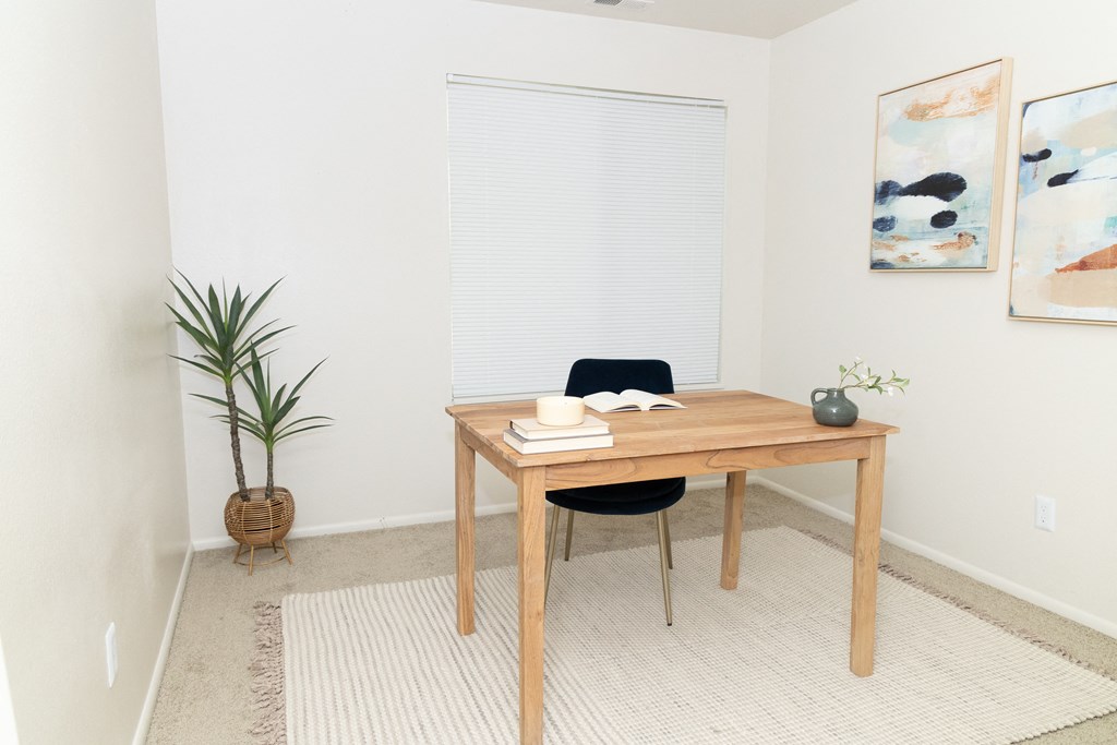 a desk and chair in a room with a window and a plant