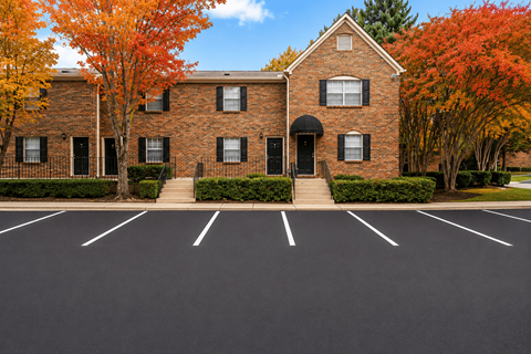 A parking lot in front of a brick building with trees in autumn colors.