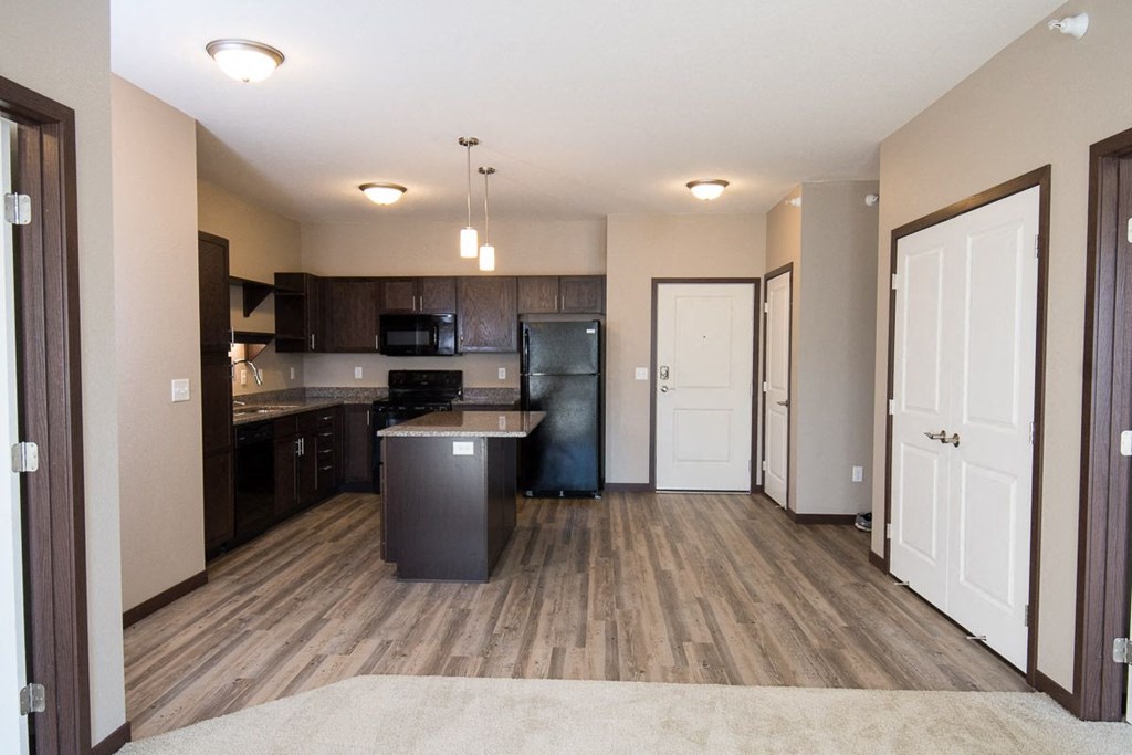 a kitchen and living room with a refrigerator and a sink