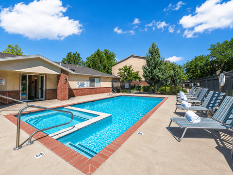 A swimming pool surrounded by lounge chairs and a building in the background.