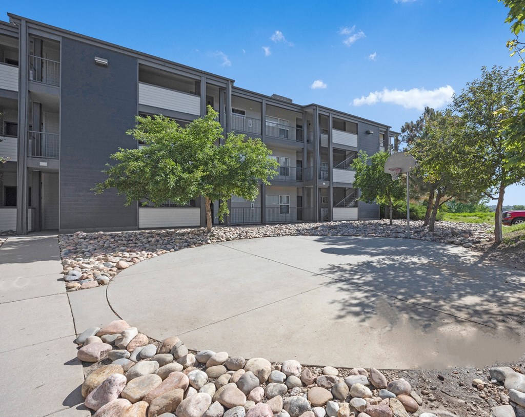 an outdoor area with trees and rocks in front of an apartment building