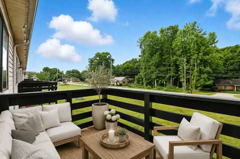 A balcony with a table and chairs overlooking a green landscape.