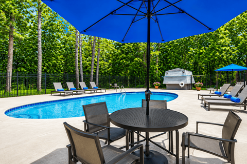A pool area with a table and chairs and an umbrella.