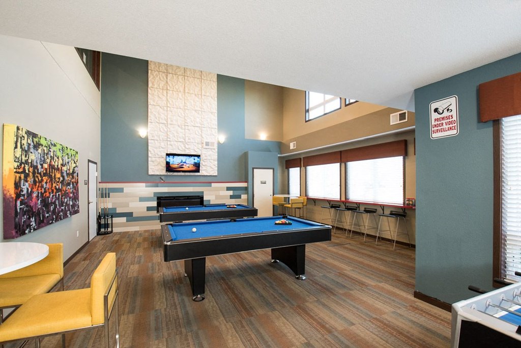 a game room with two pool tables and a tv